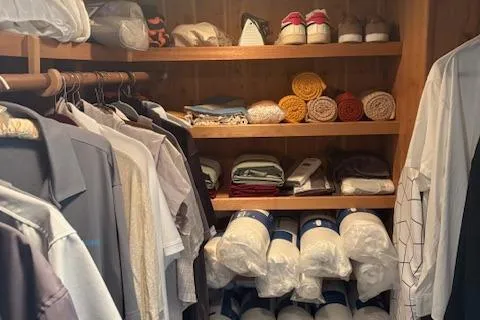Island Yacht Photos Pics Closet with neatly organized clothes, shoes, and towels on wooden shelves. Hatteras 70, 1988.