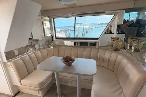 Island Yacht Photos Pics 1988 Hatteras 70 yacht interior with beige seating, table, and marina view.
