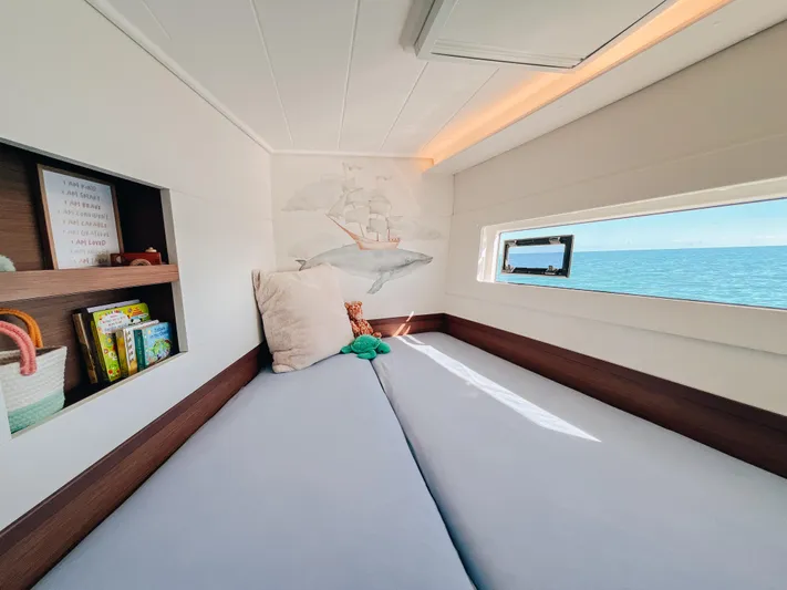Cloud II Yacht Photos Pics Cozy cabin interior of 2023 Lagoon 40 catamaran with ocean view and bookshelf.