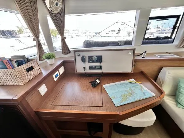 Smooth Sailor Yacht Photos Pics Navigation station in a 2019 Lagoon 450 catamaran with map, radio, and books.