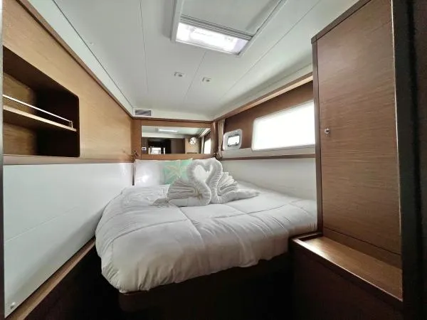 Smooth Sailor Yacht Photos Pics Luxurious cabin interior of 2019 Lagoon 450 catamaran with cozy bed and elegant wood finish.