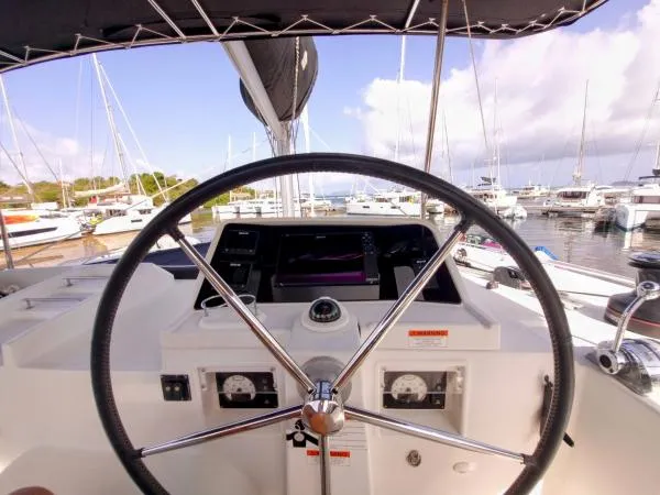 Smooth Sailor Yacht Photos Pics Steering wheel of 2019 Lagoon 450 catamaran at marina, surrounded by sailboats.