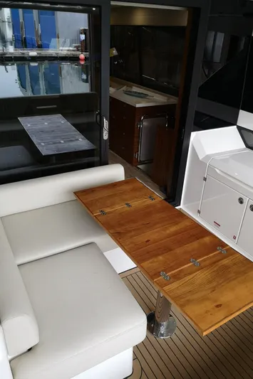 City Lights Yacht Photos Pics 2021 Maritimo X50 yacht interior with wooden table, white seating, and kitchenette.