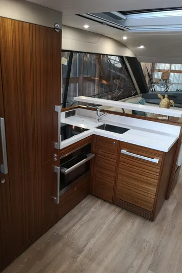 City Lights Yacht Photos Pics Modern kitchen interior of 2021 Maritimo X50 yacht with sleek wood cabinetry and white countertops.