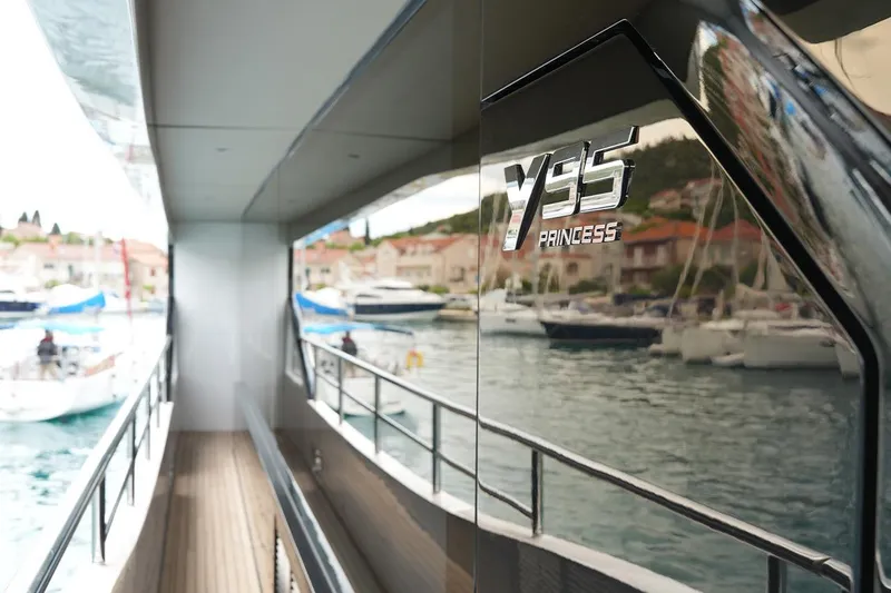  Yacht Photos Pics 2025 Princess Y95 yacht docked, reflecting marina and waterfront houses.