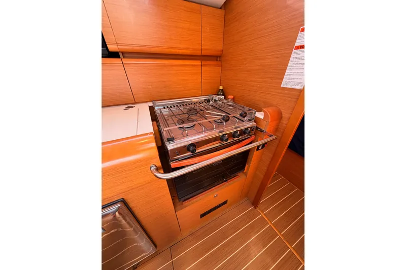 Leah Yacht Photos Pics 2014 Jeanneau Sun Odyssey 469 yacht kitchen with stove and wooden cabinetry.