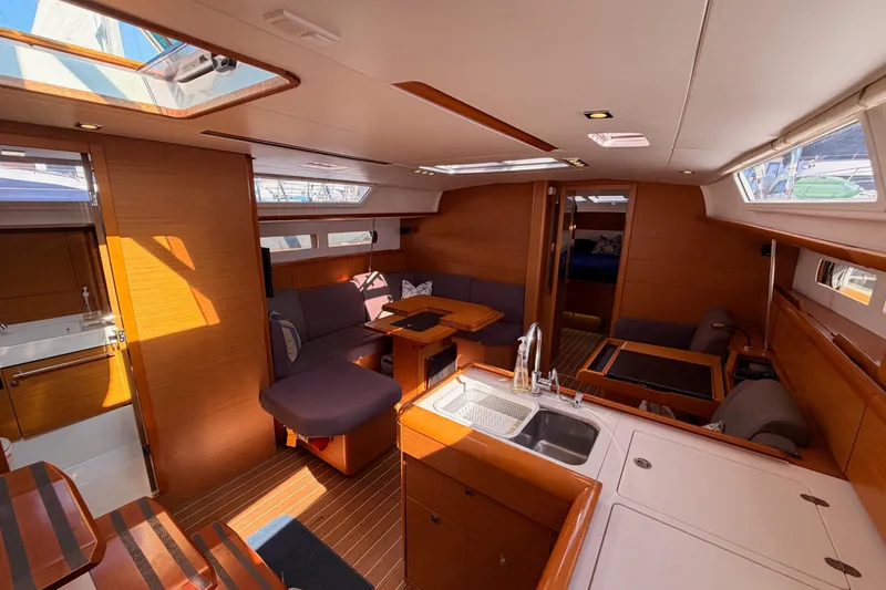 Leah Yacht Photos Pics Interior of 2014 Jeanneau Sun Odyssey 469 sailboat, featuring modern wood finishes and spacious seating.