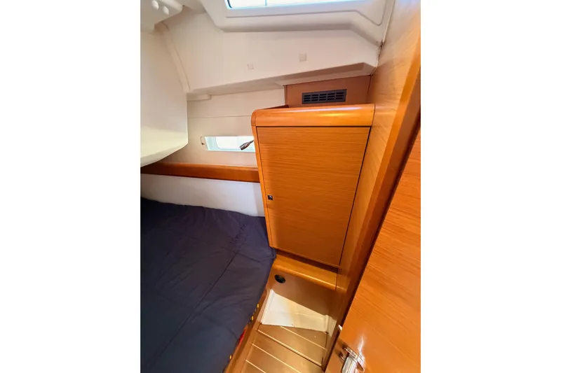 Leah Yacht Photos Pics Interior cabin of 2014 Jeanneau Sun Odyssey 469 sailboat, featuring wooden cabinetry and bedding.