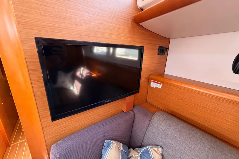 Leah Yacht Photos Pics Interior of 2014 Jeanneau Sun Odyssey 469 with wall-mounted TV and cozy seating area.