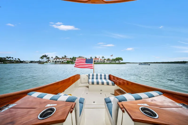 She's The One Yacht Photos Pics 2019 Hinckley Picnic Boat 34 on water, American flag, striped seating, scenic view.