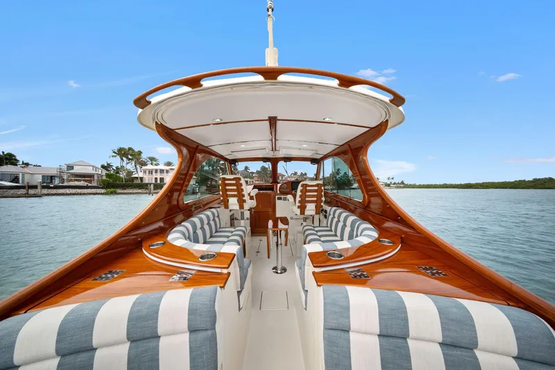 She's The One Yacht Photos Pics 2019 Hinckley Picnic Boat 34 with elegant wood finish and striped seating on calm water.