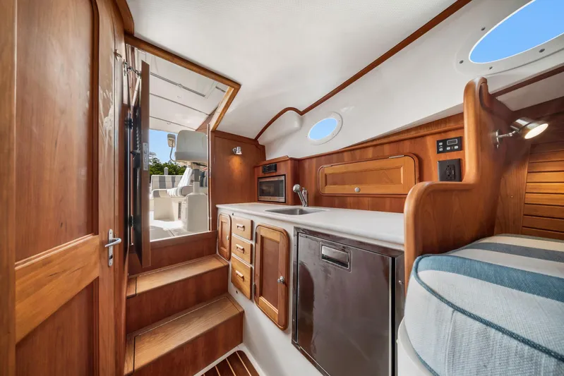 She's The One Yacht Photos Pics 2019 Hinckley Picnic Boat 34 interior with wood cabinetry, compact kitchen, and cozy seating.
