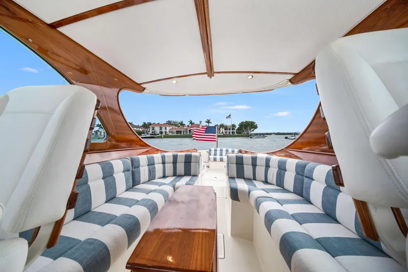 She's The One Yacht Photos Pics 2019 Hinckley Picnic Boat 34 interior with striped seating and wooden accents, overlooking water.