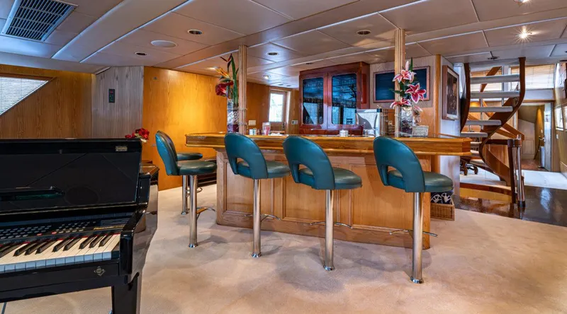 Le Montrachet Yacht Photos Pics Luxurious 1986 Broward Flybridge interior with bar, piano, and spiral staircase.