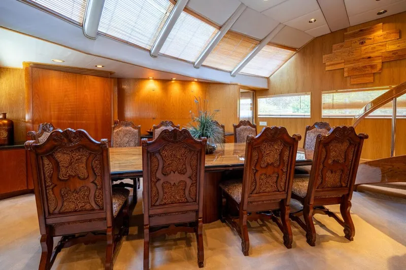 Le Montrachet Yacht Photos Pics Luxurious dining area on 1986 Broward Flybridge yacht with elegant wooden chairs and table.