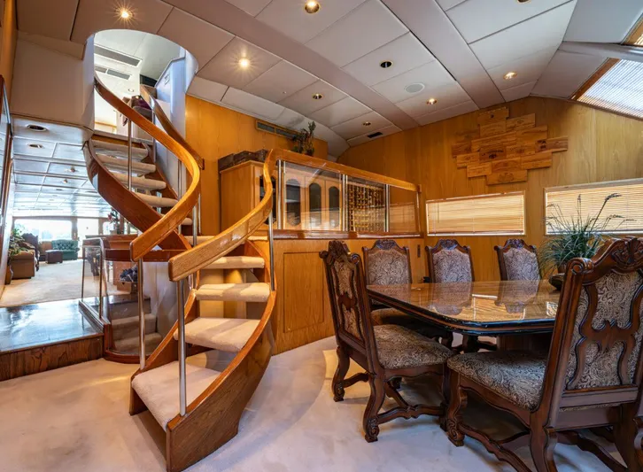 Le Montrachet Yacht Photos Pics Luxurious 1986 Broward Flybridge yacht interior with elegant dining area and spiral staircase.