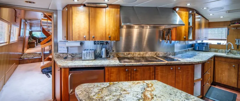 Le Montrachet Yacht Photos Pics Luxurious 1986 Broward Flybridge yacht kitchen with granite countertops and wooden cabinetry.