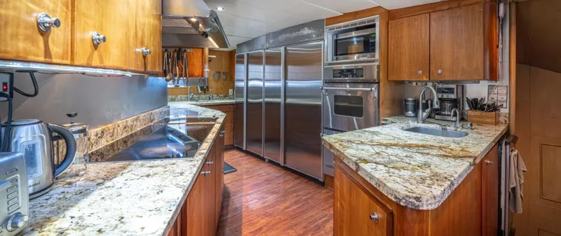 Le Montrachet Yacht Photos Pics Luxurious kitchen interior of 1986 Broward Flybridge yacht with granite countertops and stainless steel appliances.