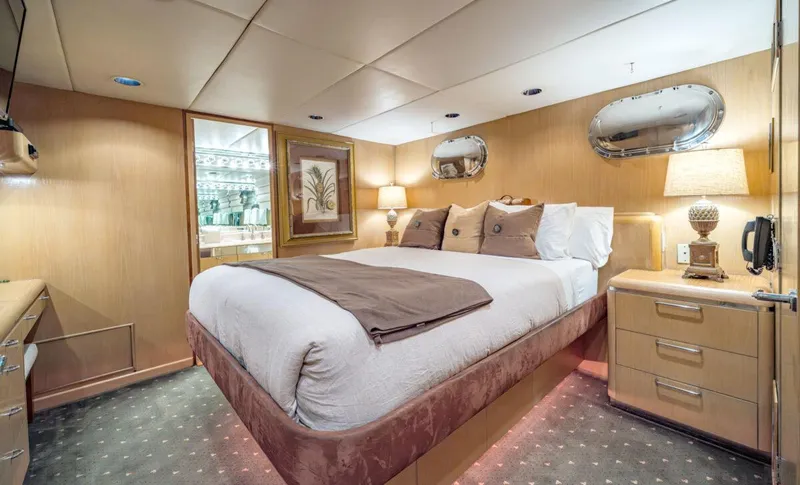 Le Montrachet Yacht Photos Pics Luxurious bedroom interior of 1986 Broward Flybridge yacht with elegant decor and ambient lighting.
