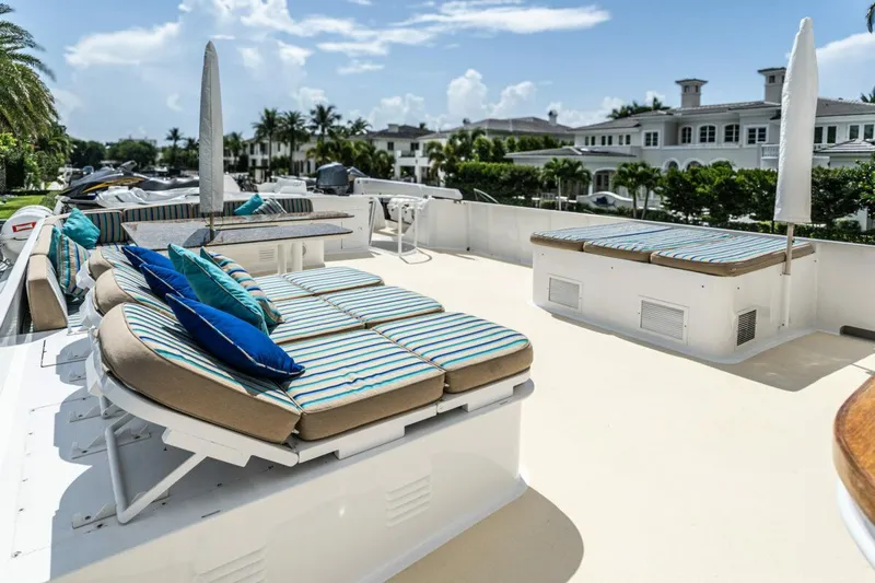 Le Montrachet Yacht Photos Pics 1986 Broward Flybridge yacht deck with striped lounge chairs and umbrellas.