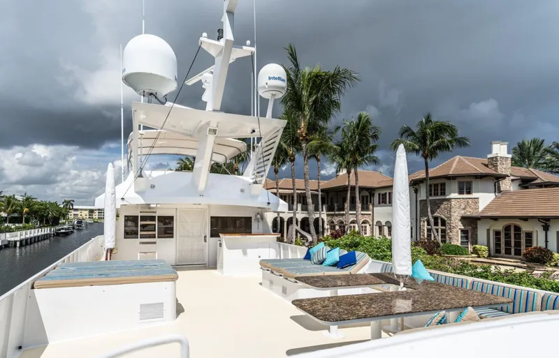 Le Montrachet Yacht Photos Pics 1986 Broward Flybridge yacht with spacious deck, luxury seating, and tropical backdrop.