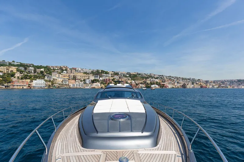 Mylo Yacht Photos Pics 2014 Pershing 74 yacht cruising near a coastal city under a clear blue sky.