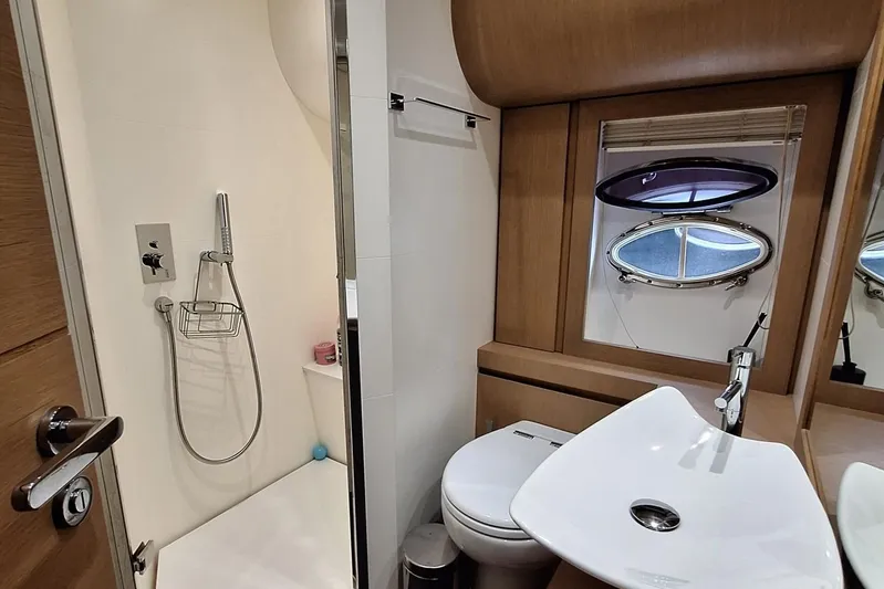 Mylo Yacht Photos Pics Luxurious bathroom in 2014 Pershing 74 yacht with modern fixtures and porthole window.