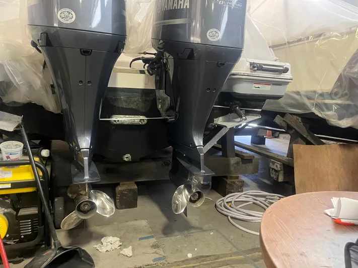  Yacht Photos Pics 2021 Robalo R272 Center Console with dual Yamaha outboard motors in a workshop setting.
