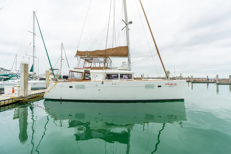 Audacity Yacht Photos Pics 2013 Lagoon 450 catamaran docked in a marina, reflecting on calm water.
