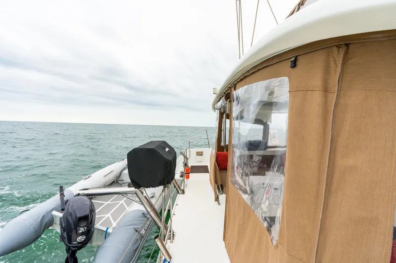 Audacity Yacht Photos Pics 2013 Lagoon 450 catamaran with dinghy on open sea, overcast sky.