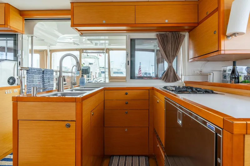 Audacity Yacht Photos Pics Luxurious kitchen interior of 2013 Lagoon 450 yacht with modern amenities and wooden cabinetry.
