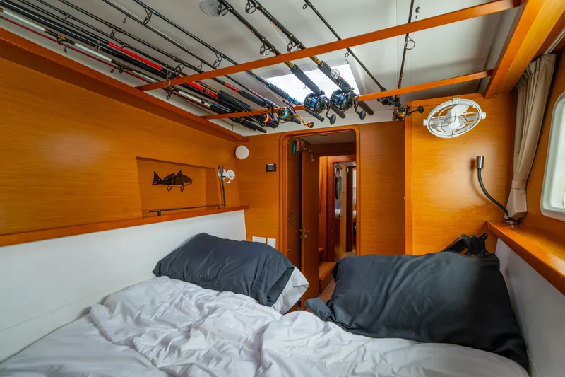 Audacity Yacht Photos Pics Cozy cabin interior of 2013 Lagoon 450 catamaran with fishing rods and twin beds.