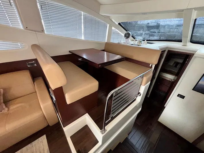  Yacht Photos Pics Interior of 2013 Sea Ray 450 Sedan Bridge with beige seating and wooden table.