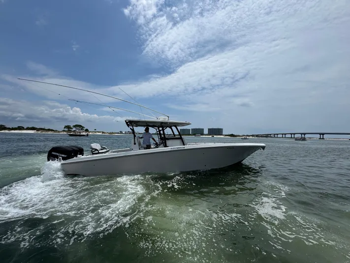  Yacht Photos Pics 2021 Fountain 38TE boat cruising on open water near a bridge and shoreline.