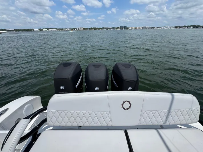  Yacht Photos Pics 2021 Fountain 38TE boat with triple Mercury engines on a calm water backdrop.
