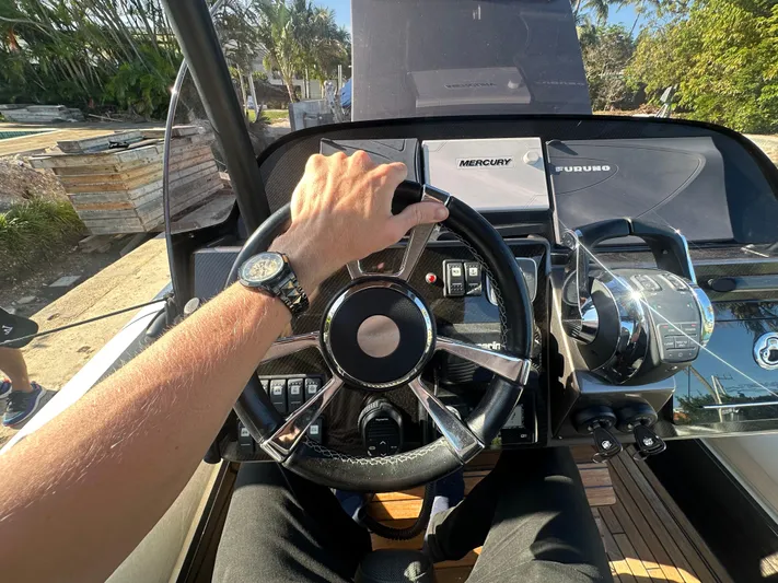  Yacht Photos Pics Person steering 2020 Technohull SEADNA 999 G5 ST boat, showcasing dashboard controls.