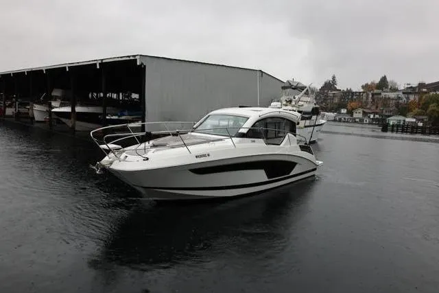  Yacht Photos Pics 2021 Four Winns V355 Coupe boat on water near dock, overcast sky.