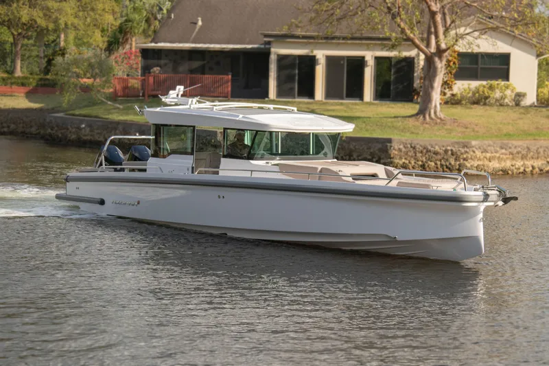  Yacht Photos Pics 2024 Axopar 37XC CROSS CABIN cruising on a calm river near a house.