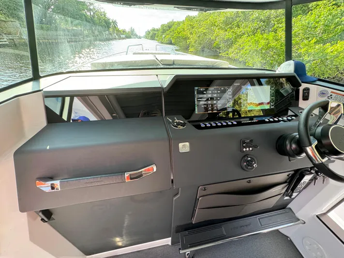  Yacht Photos Pics 2024 Axopar 37XC CROSS CABIN helm with modern controls and scenic waterway view.