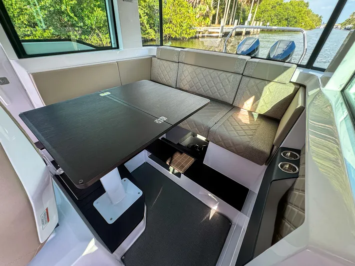  Yacht Photos Pics 2024 Axopar 37XC CROSS CABIN interior with seating and table, featuring modern design and waterfront view.