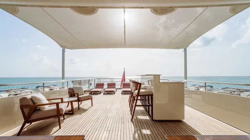 Midnight Saga Yacht Photos Pics Luxurious 2023 Moonen 110 yacht deck with seating, bar, and ocean view.