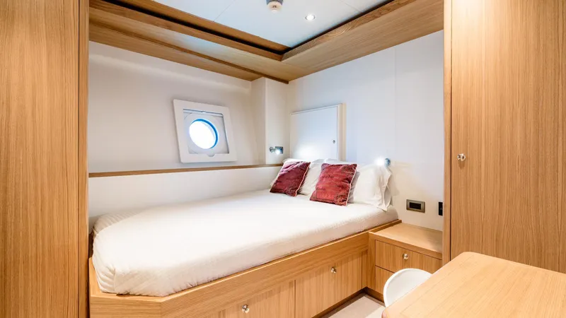 Midnight Saga Yacht Photos Pics Luxurious cabin interior of 2023 Moonen 110 yacht with wooden furnishings and porthole window.