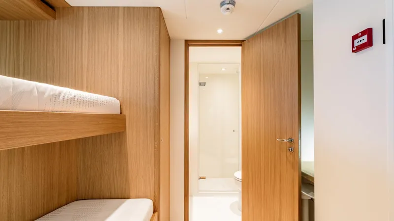 Midnight Saga Yacht Photos Pics Interior of 2023 Moonen 110 yacht with wooden bunk beds and open bathroom door.