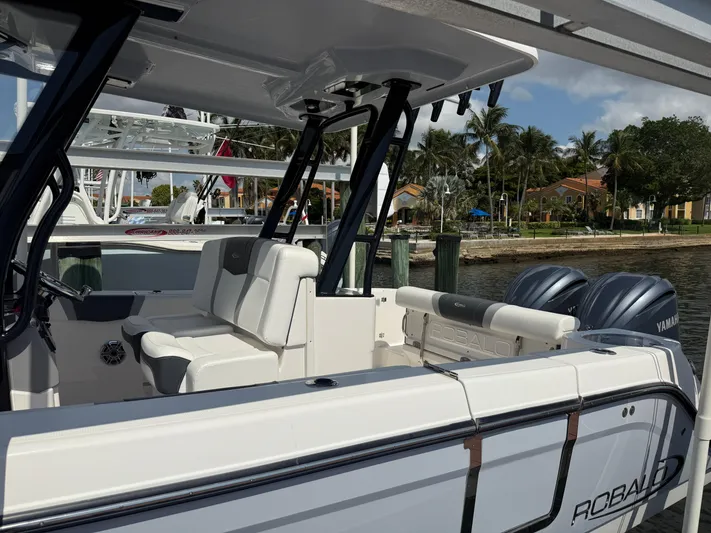 272-203 Brokerage Sebastian Yacht Photos Pics 2023 Robalo R272 Center Console boat docked by palm trees and waterfront homes.