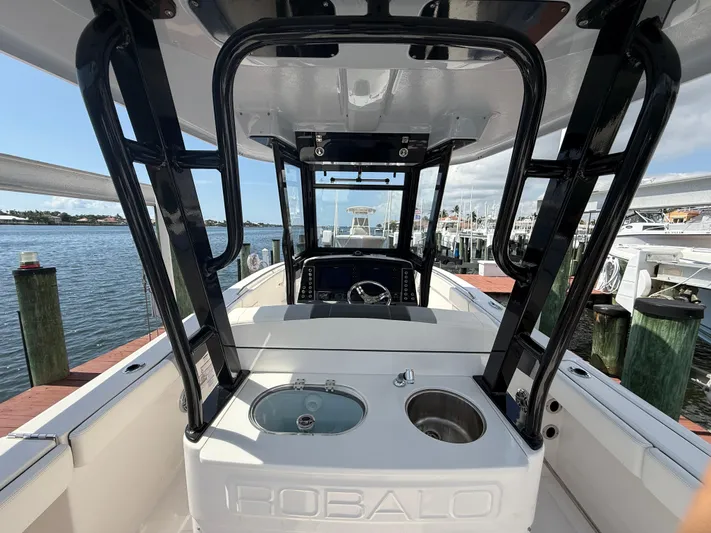 272-203 Brokerage Sebastian Yacht Photos Pics 2023 Robalo R272 Center Console boat interior with helm and seating, docked by the water.