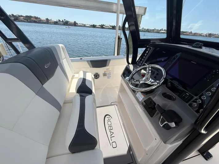 272-203 Brokerage Sebastian Yacht Photos Pics 2023 Robalo R272 Center Console boat interior with steering wheel and seating, overlooking water.