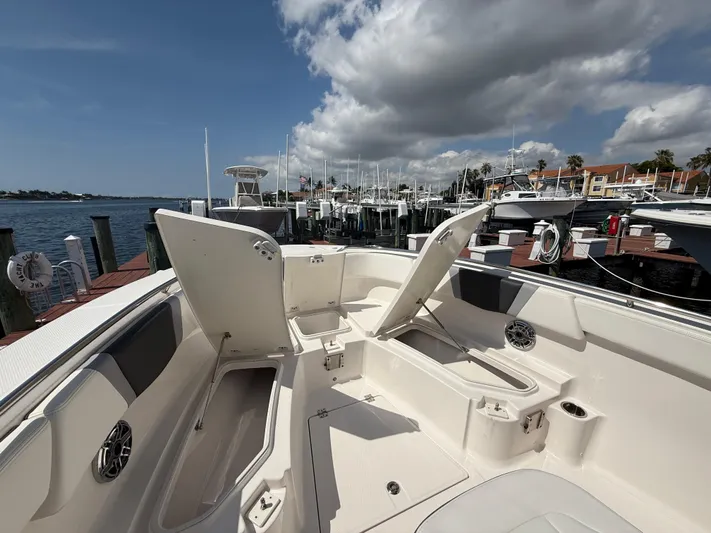 272-203 Brokerage Sebastian Yacht Photos Pics 2023 Robalo R272 Center Console boat docked, open storage compartments, sunny marina view.