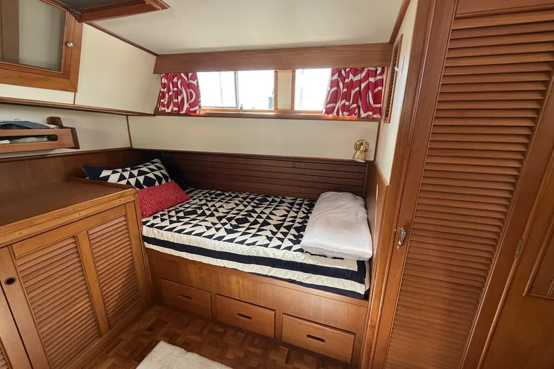  Yacht Photos Pics Cozy cabin interior of 1999 Grand Banks 42 Classic with wooden furnishings and patterned bedding.