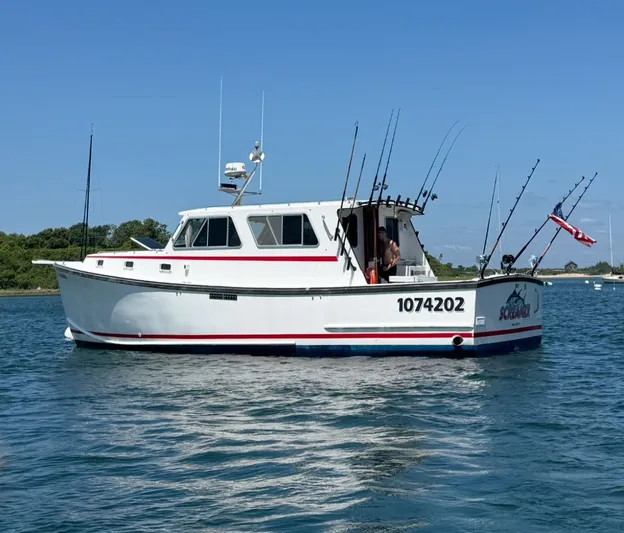 Screamer Yacht Photos Pics 1998 Wilbur 38 Downeast boat on water, equipped with fishing rods and American flag.