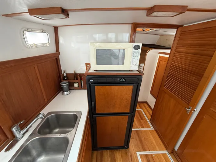 Screamer Yacht Photos Pics 1998 Wilbur 38 Downeast boat interior with kitchenette, featuring microwave, fridge, and double sink.